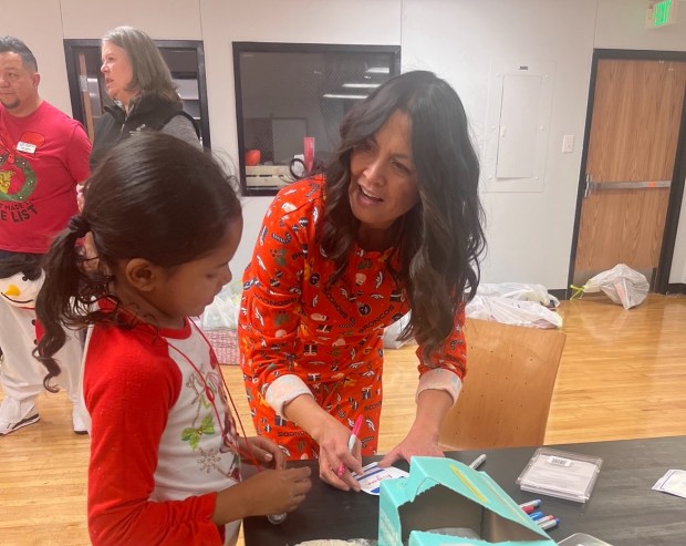 Barb Paton, wife of Broncos GM George Paton, helps a child at a gift wrapping station during a past Holiday Huddle event.